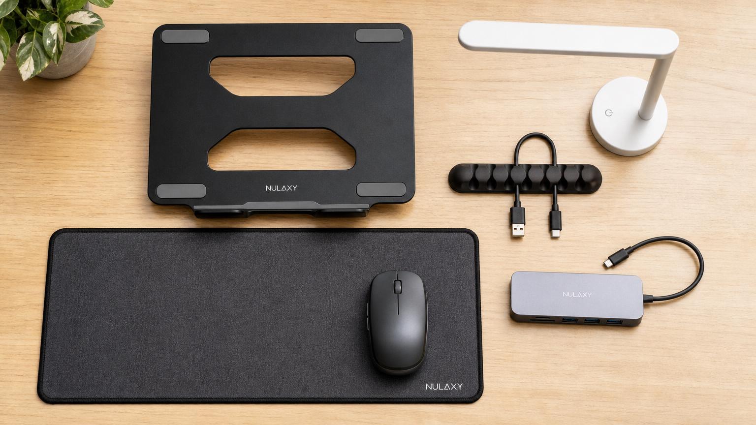 Cinco acessórios de mesa organizados em flat lay: hub USB, cabo, suporte, luminária e mousepad